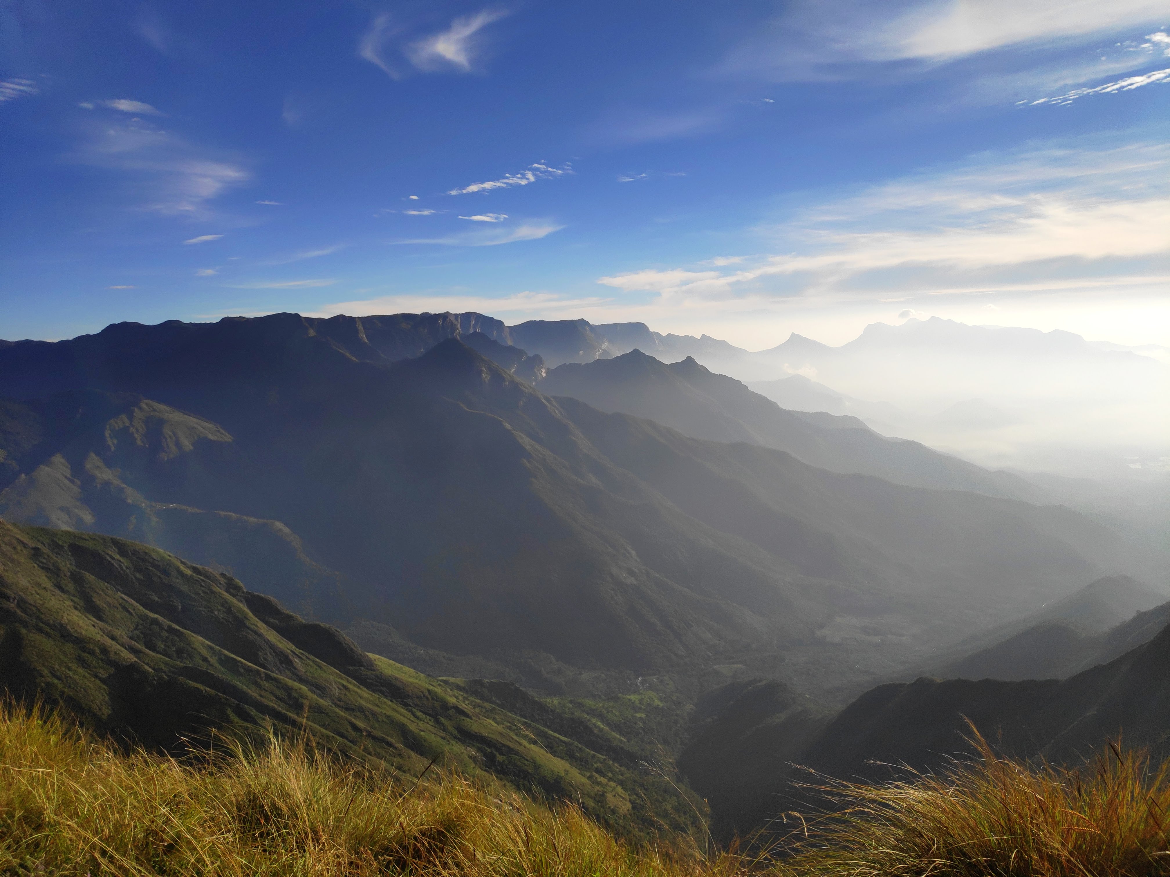 Mountains in the morning sunlight with greenery and some grass in the foreground.