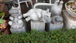 A couple of cement hippos sitting on top of cement blocks. 
