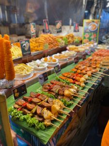 View larger photo: Food for sale in a market. Many varieties of meat and vegatables on skewers.