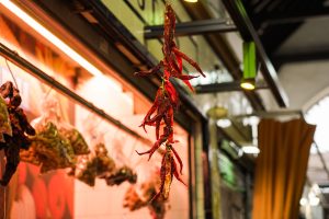 String of red chillies hanging on a market stall.