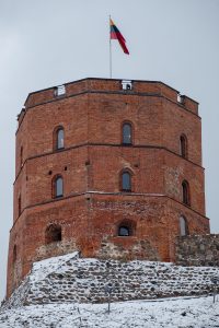 Gediminas Castle Tower, Vilnius. It’s a brick turret with a flag on top and snow on the roof below it.
