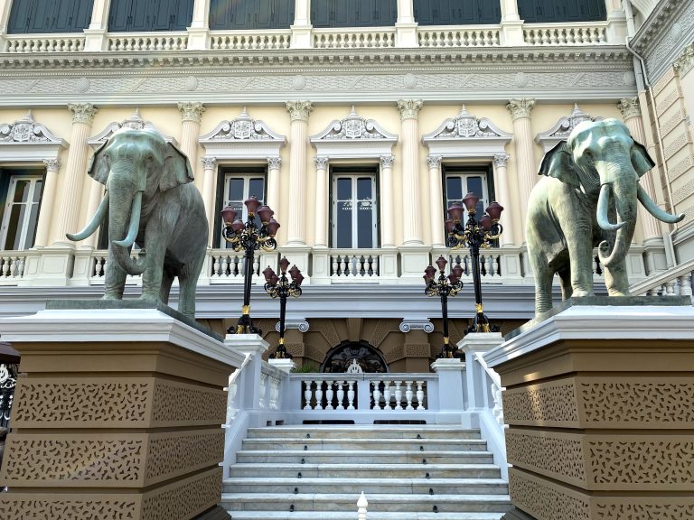 Staircase to an ancient building guarded by two elephant statues.