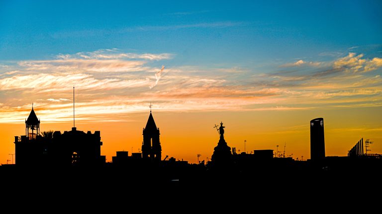 Seville city skyline with silhouetted buildings and clouds during sunset.