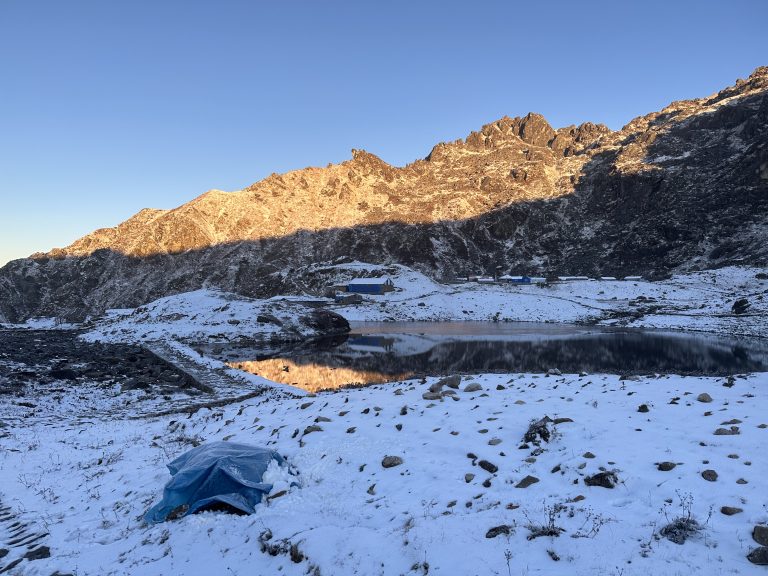 Snow-covered hill, first ray of sunshine on snow, lake