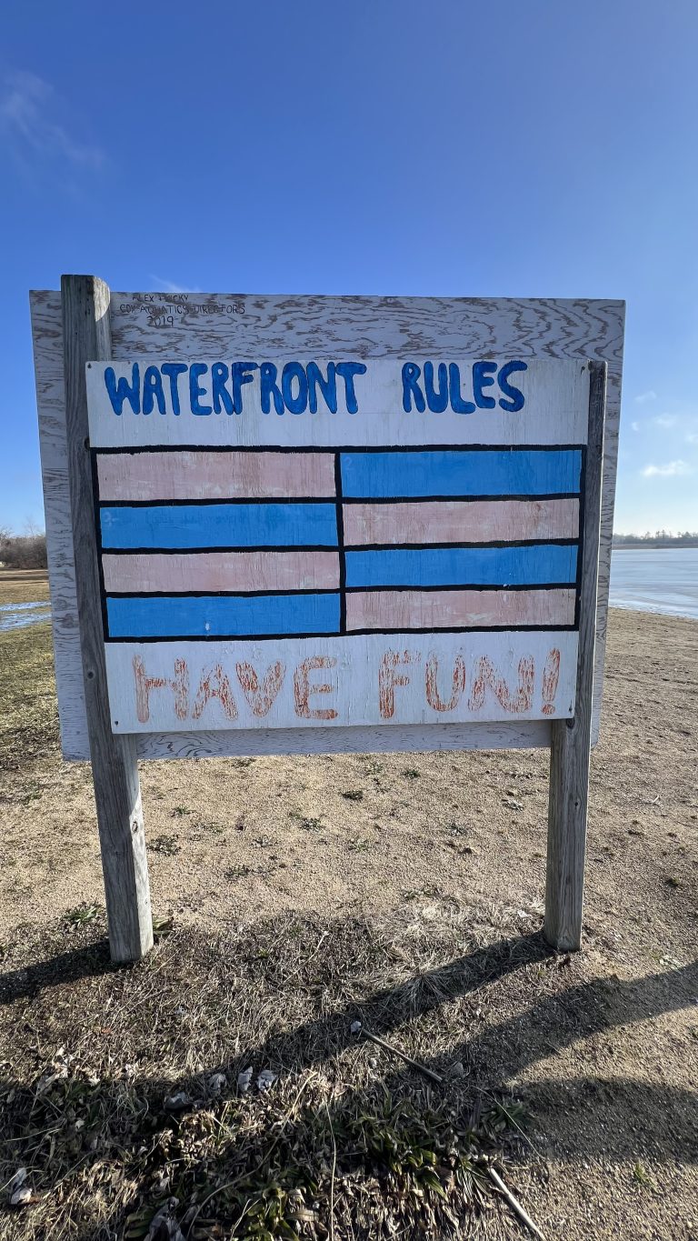 Handmade wood sign on the Fish Lake beachfront stating “Waterfront Rules, Have Fun!” (YMCA Camp Duncan, Ingleside, Illinois).