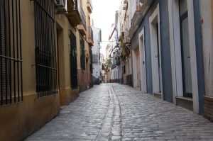 Small stone-paved street between buildings in the center of Sevilla, Spain