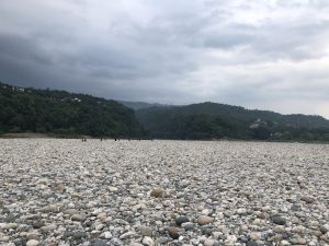 A large field of stones. People walk far away with mountains in the background.