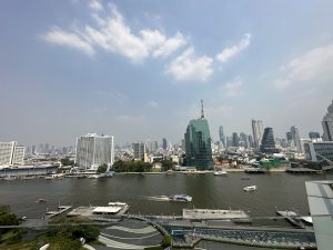 Boats on the river in Bangkok with highrise buildings on the banks
