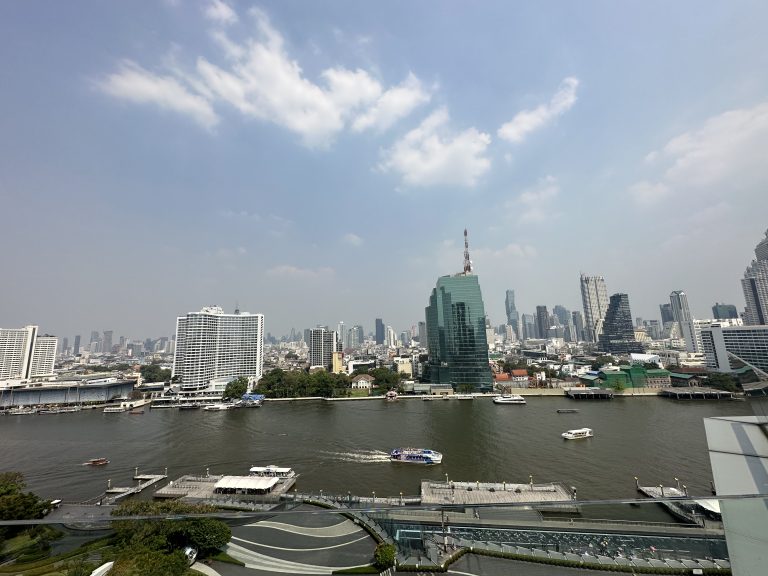 Boats on the river in Bangkok with highrise buildings on the banks