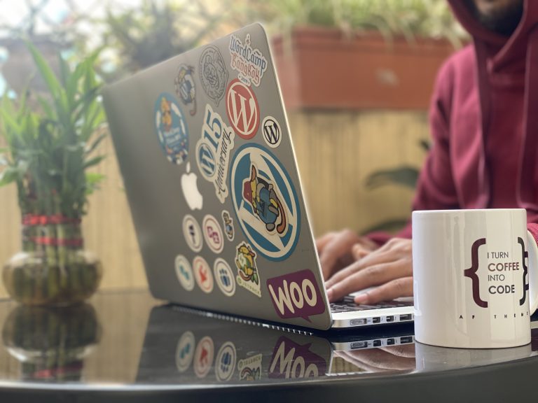 Man working on a Laptop with colorful stickers, representing achievements and community bonds. Embrace the joy of creating!