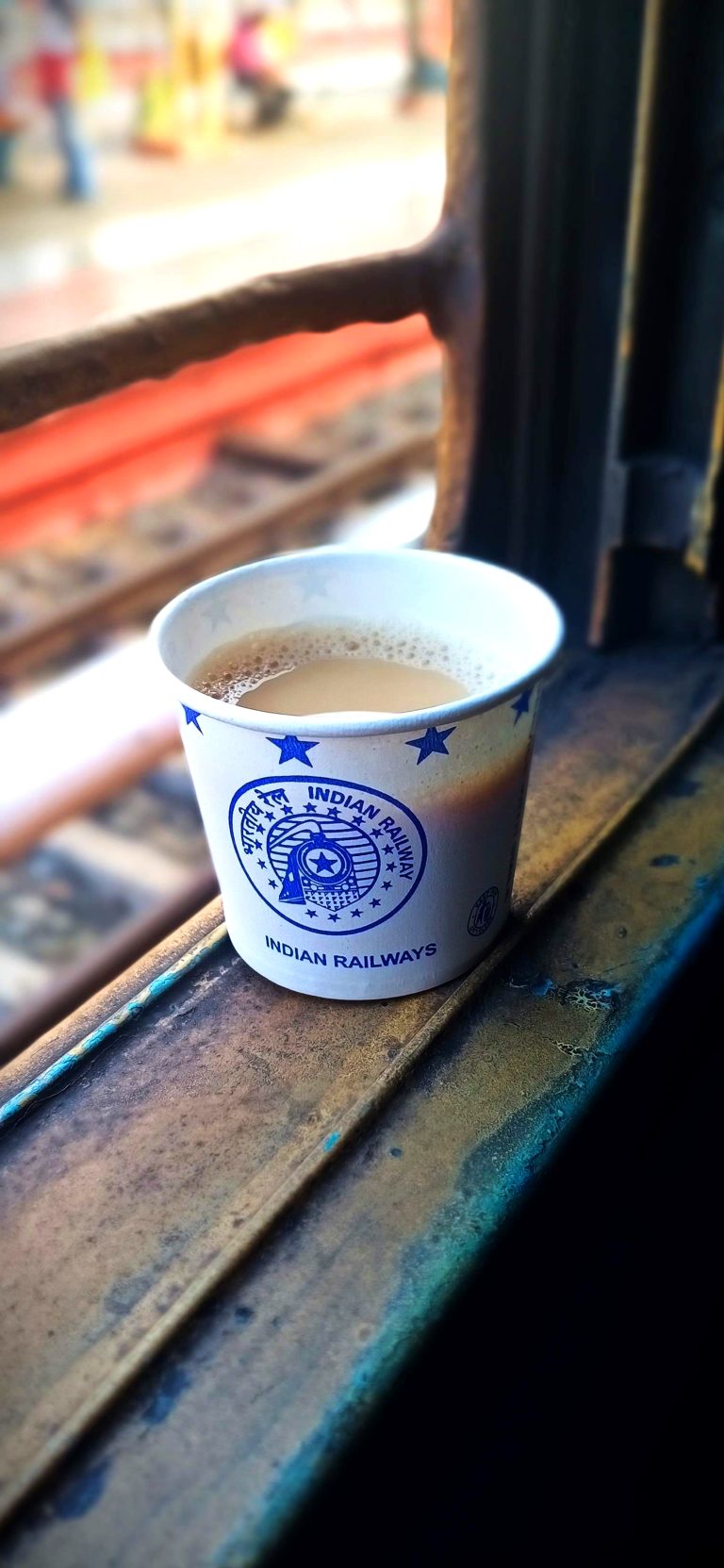 A cup of coffee placed near a window in a train.