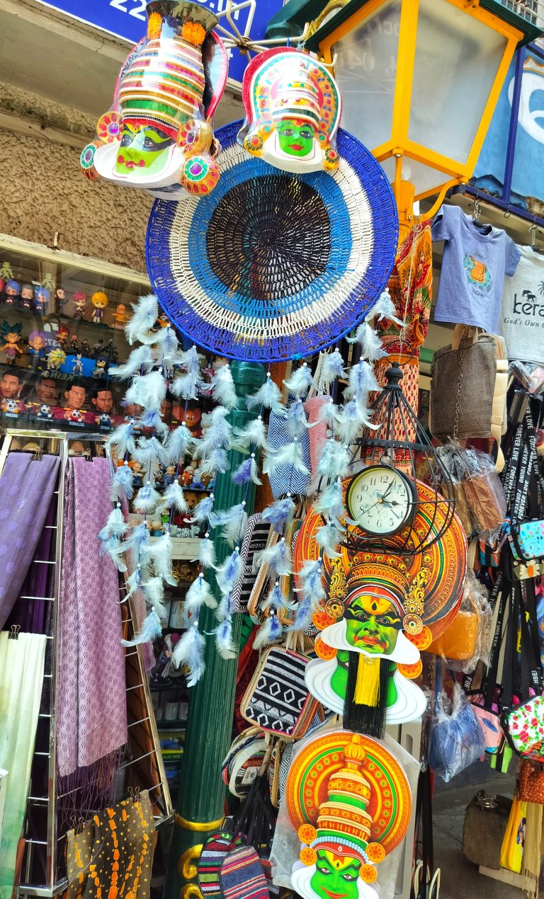 Dreamcatchers, Kathakali figures, dolls, a clock, and more at a vendor stand