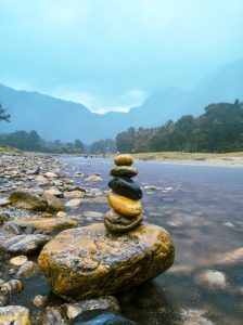 Stacked stones on the shore of a river with tall mountain ranges in the background. Kariyathumpara, Kozhikode.