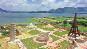  Miniature replicas of the Seven Wonders of the World displayed in a frame near a river. 
