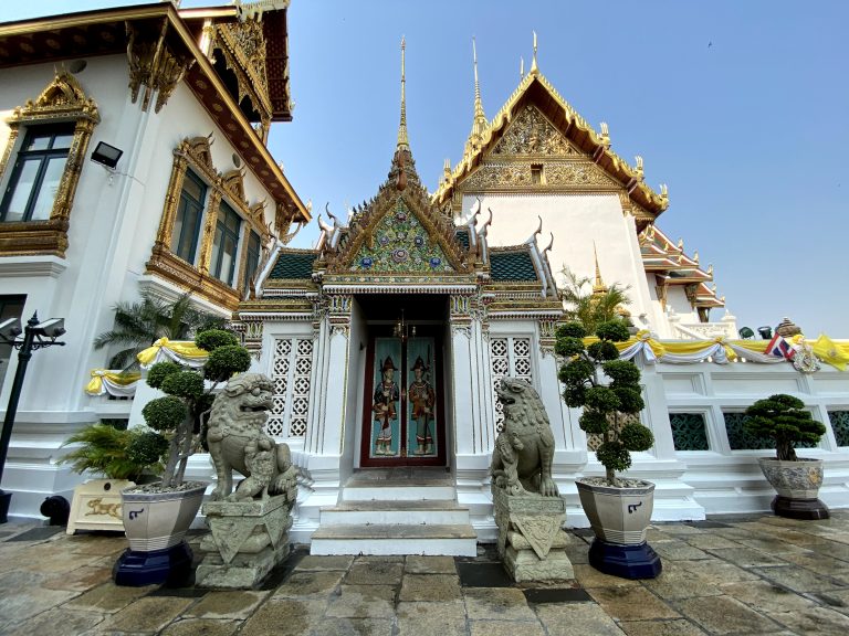 A large white ancient building with statues in front of it