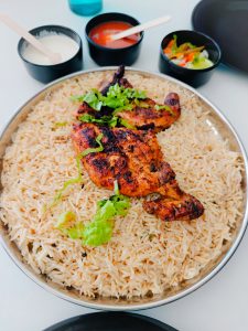 Kuzhi mandhi. A plate of fragrant rice with grilled chicken on top served along with salads and mayo.