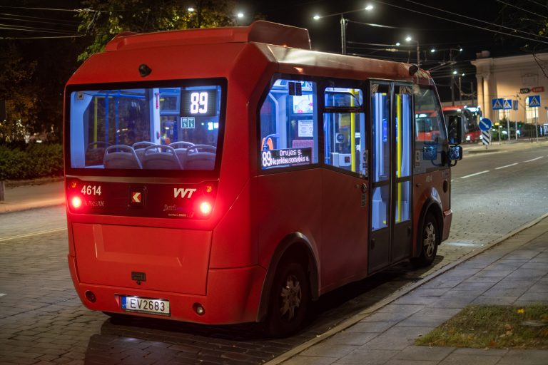 Empty public transport vehicle driving up to the Vilnius train station at night time.