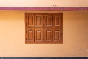 Closed, swinging wooden windows on a peach colored wall 