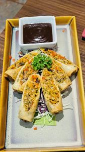 Delicious spring rolls served on a tray with dipping sauce.