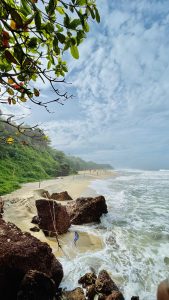 The beack at Varkala, India. Waves lap at the sandy beach. Trees and green plants line the beach.