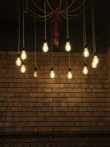 Lights are hanging from the ceiling and a brick wall in the Background.