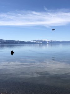 Seaplane flying over Agate Bay with snow-capped mountains in the background (Lake Tahoe, Tahoe Vista, California)
