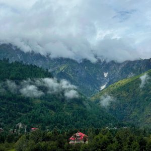 A red roofed building in the valley of a mountain covered with fog. 