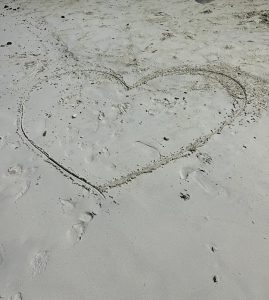A heart drawin into the sand on a beach
