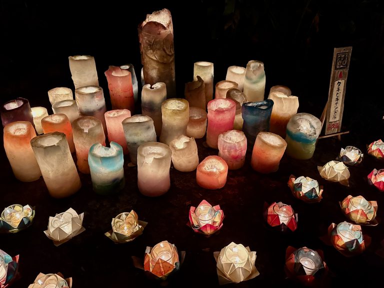 Dozens of lit candles in different shapes and sizes. Memorial, prayer, vigil, night, light, lights, ceremony, festival.