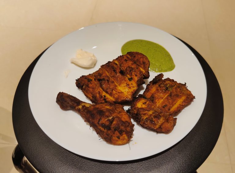 Delicious homemade Chicken Al Faham served on a white plate with mint chutney and mayonnaise.