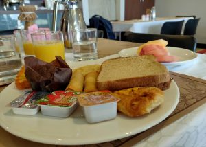 A delightful spread of breakfast offerings including cake, juice, wheat bread, and fruits.