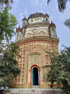 View larger photo: The entrance of a temple, the temple has many golden mini statues on it. On the left and the right of the entrance there are trees.