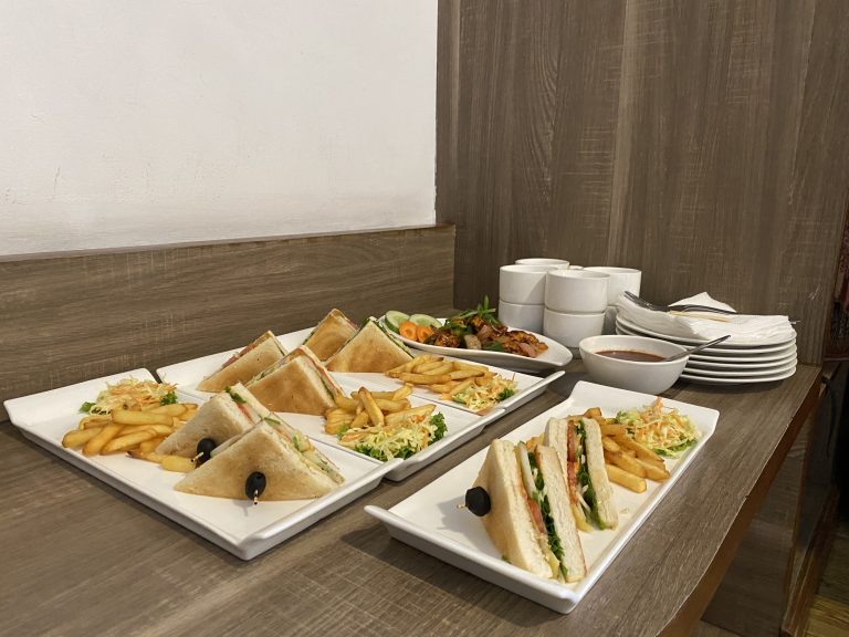 Breakfast. Sandwiches and fries served on a white tray with dippings on a table.