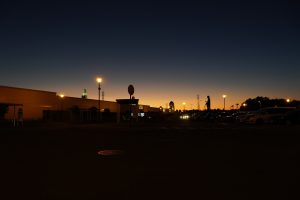 Night time, with glowing streetlights and cars parked along a road.