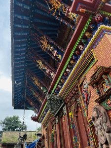 view of a colorful temple with sculptures of deities on the wall and the roof.