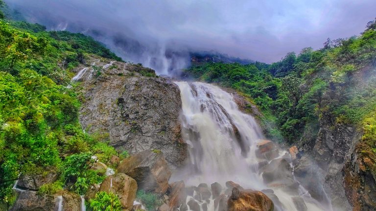 View of a waterfall surrounded by a lush forest. Kynrem Falls, Meghalaya