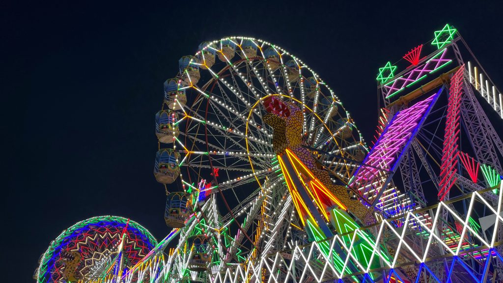 Giant wheels and a Dragon swing boat illuminated with colorful lights