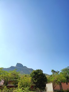 Nature's Palette Embracing the serenity of a blue sky, lush green trees, and majestic mountains.