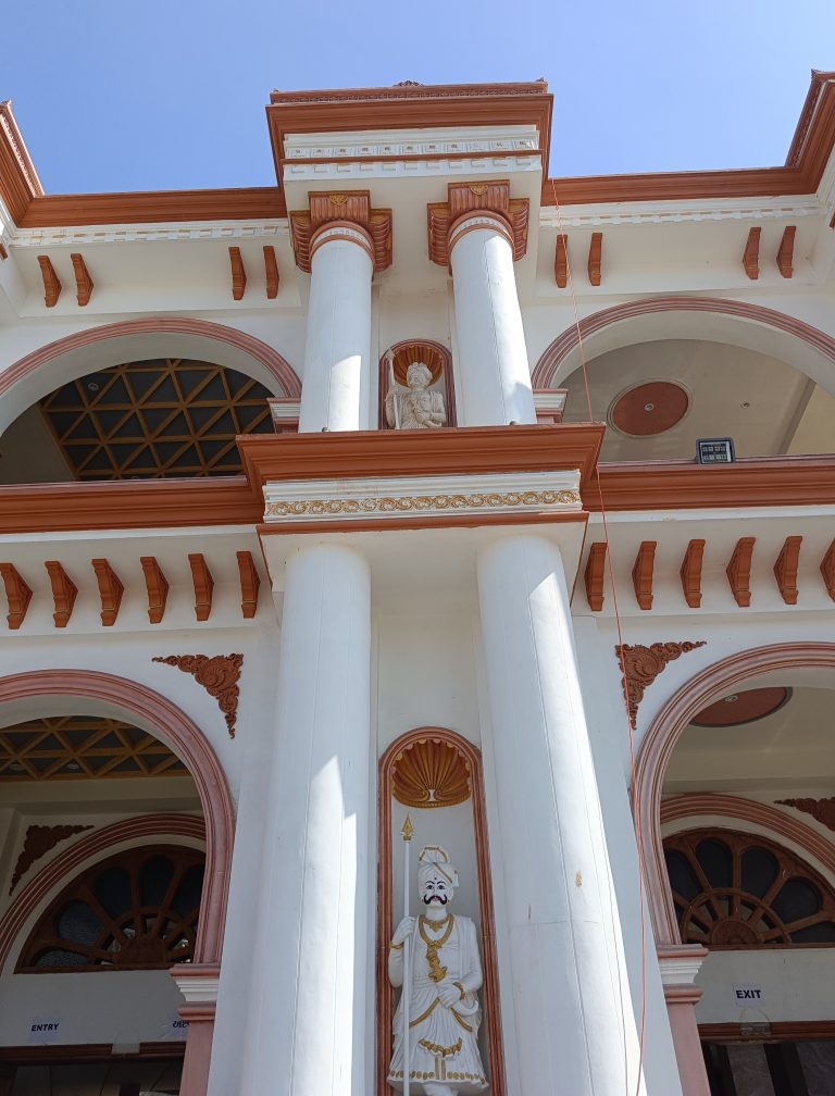 Two statues are part of the exterior design of a grand two-story building