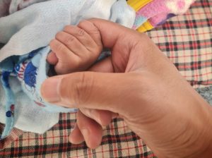 Infant grasping onto an adult's finger.