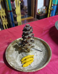 A copper incense stick stand on a red tablecloth