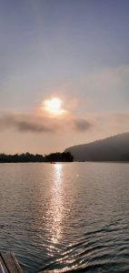 Fewa Lake reflects the sun's golden light while clouds obscure the sun.