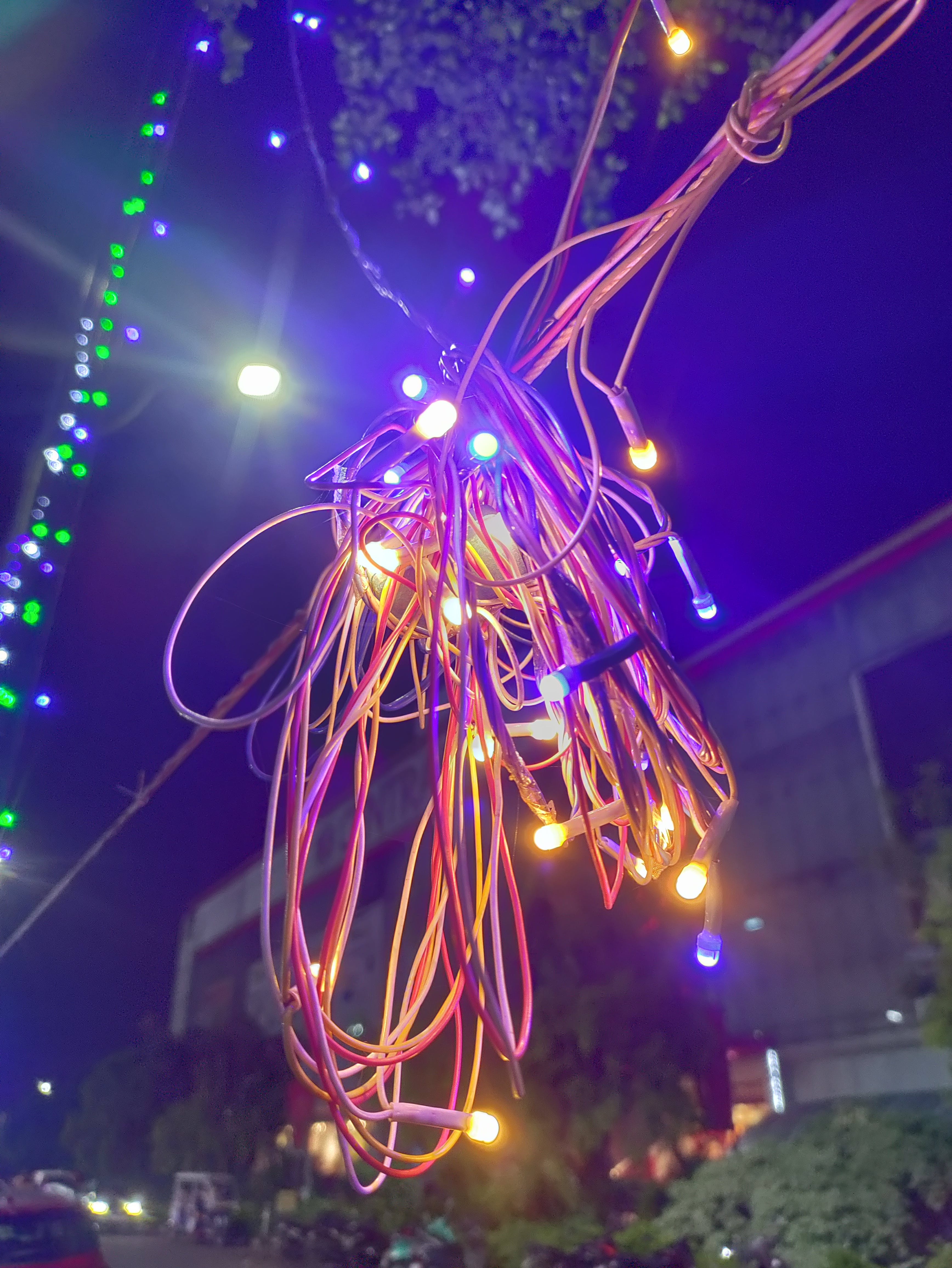 Disordered LED bulbs with wires protruding within a strand along a roadway.