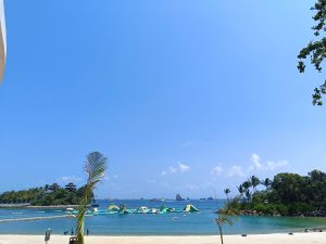 Tropical paradise on Sentosa Island, Singapore, featuring sandy beach, palm trees, and azure water.

