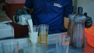 Making of the refreshing milk sarbath. A man is pouring milk to a glass containing syrup.