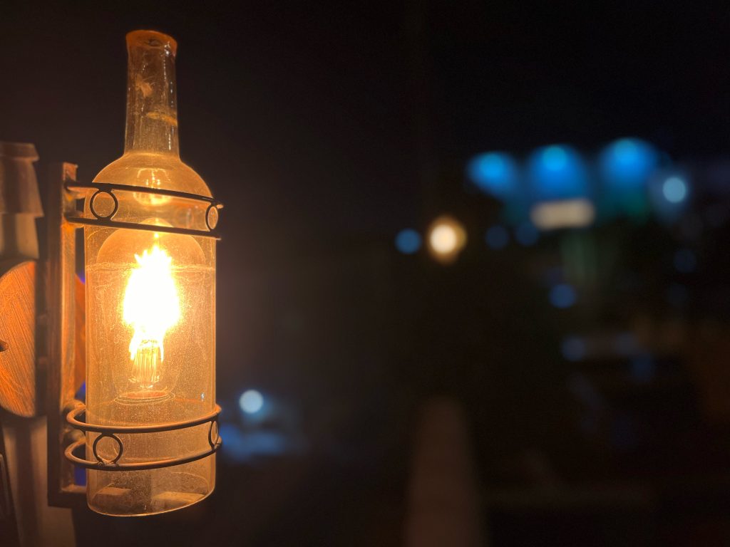 Upcycled glass bottle light fixture: Creative restaurant decor, eco-friendly lighting solution, repurposed glass adds unique charm.