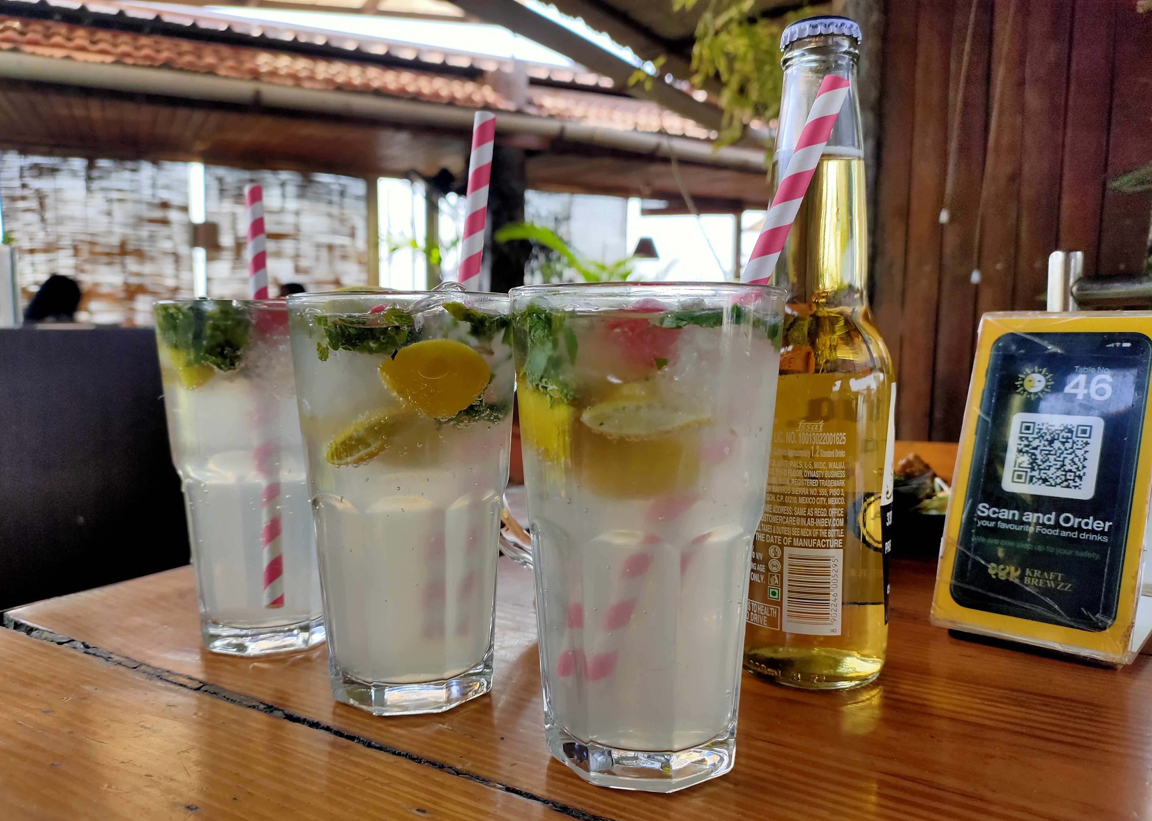 A delightful spread of refreshing mocktails and a chilled bottle of beer, set on a sunlit table.