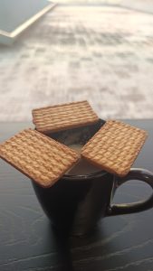 Three biscuits are arranged on the black tea cup.
