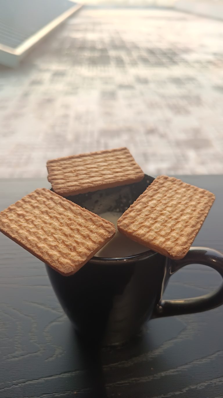 Three biscuits are arranged on the black tea cup.