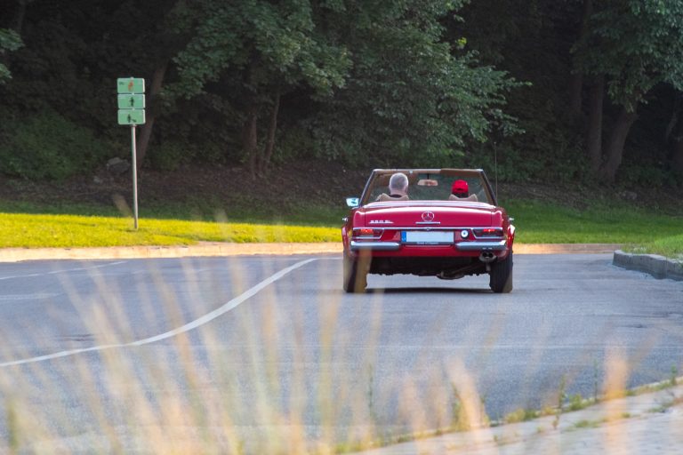 A couple riding in a red convertible classic car.